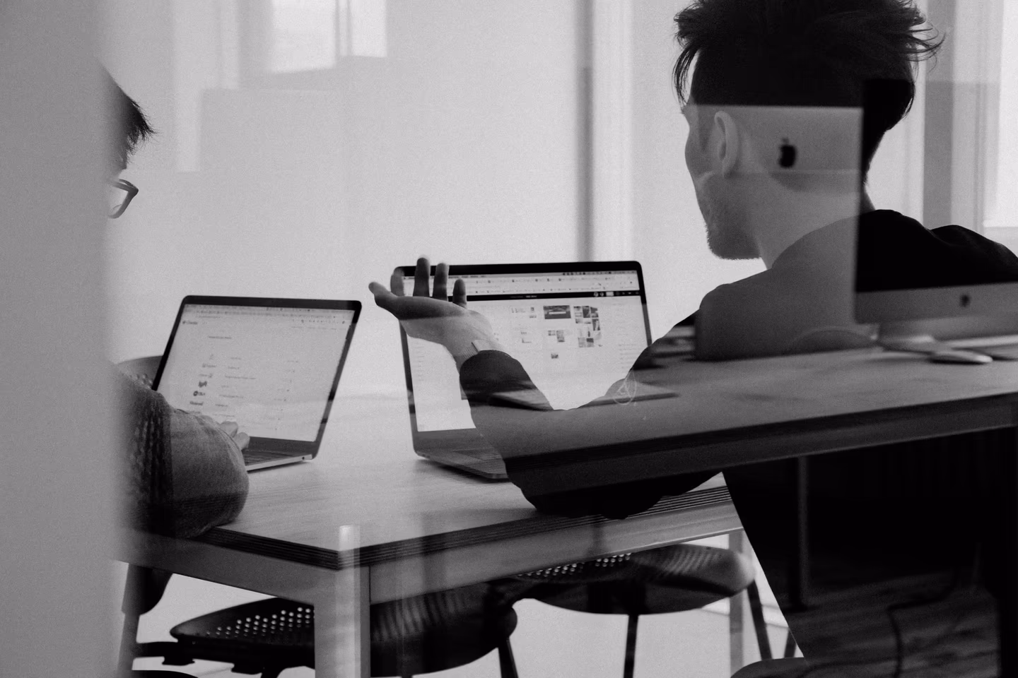 Dos personas revisan información en computadoras durante una reunión